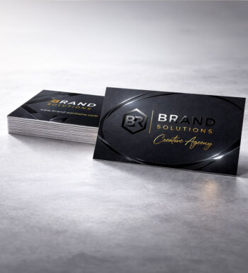 A stack of black business cards that shine only on certain areas by using the Spot UV technique where gloss is applied to a few areas instead of the whole card making logos and other parts stand out.