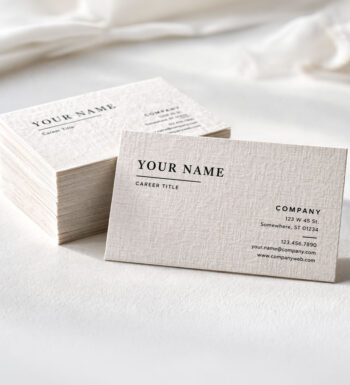 A stack of classic business cards made from linen. A linen cloth is draped across the background symbolizing the texture.