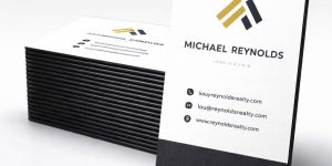 A stack of black edge painted business cards with one card positioned vertically.