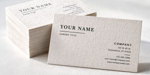 A stack of classic business cards made from linen. A linen cloth is draped across the background symbolizing the texture.