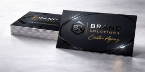A stack of black business cards that shine only on certain areas by using the Spot UV technique where gloss is applied to a few areas instead of the whole card making logos and other parts stand out.